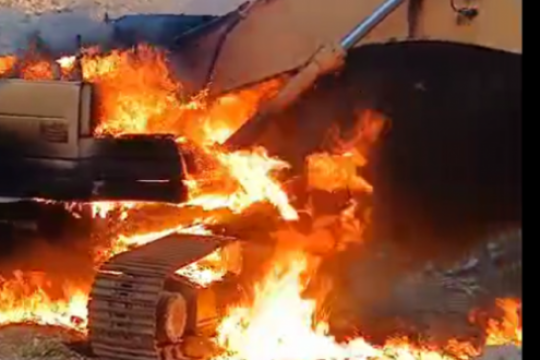 مستوطنون يحرقون حفارًا فلسطينياً ويخطّون شعارات عنصرية جنوب الضفة